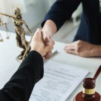 Lawyer or attorney shakes hands to agree on the client's offer to be hired to fight the parties in court