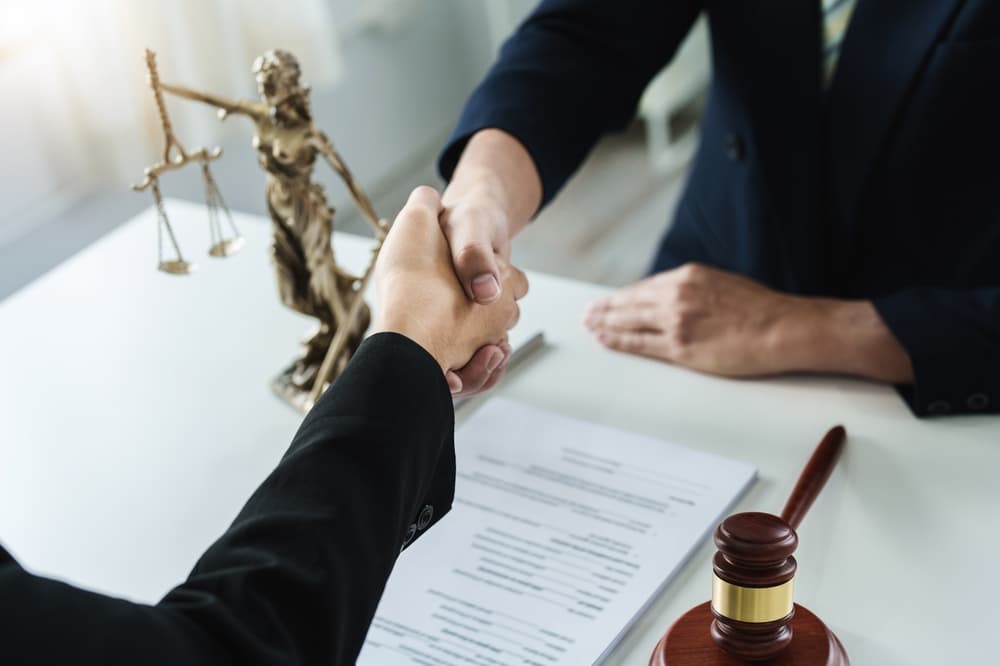 Lawyer or attorney shakes hands to agree on the client's offer to be hired to fight the parties in court