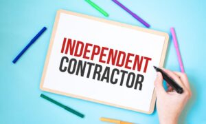 The text "Independent Contractor" is written on a notebook surrounded by colored felt-tip pens, representing a business concept idea. 