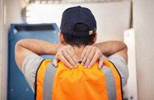 A construction worker experiencing back pain from building, home renovation, or handyman work. The image suggests the need for massage therapy and highlights the risks of accidents for workers or contractors.