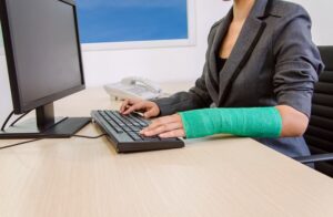 Injured Businesswoman Typing on a Computer Keyboard with One Hand.