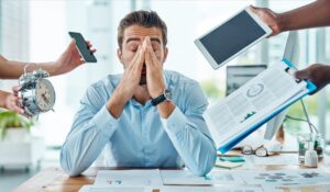 Overwhelmed by demands and deadlines, a young businessman looks stressed in a high-pressure office environment. 