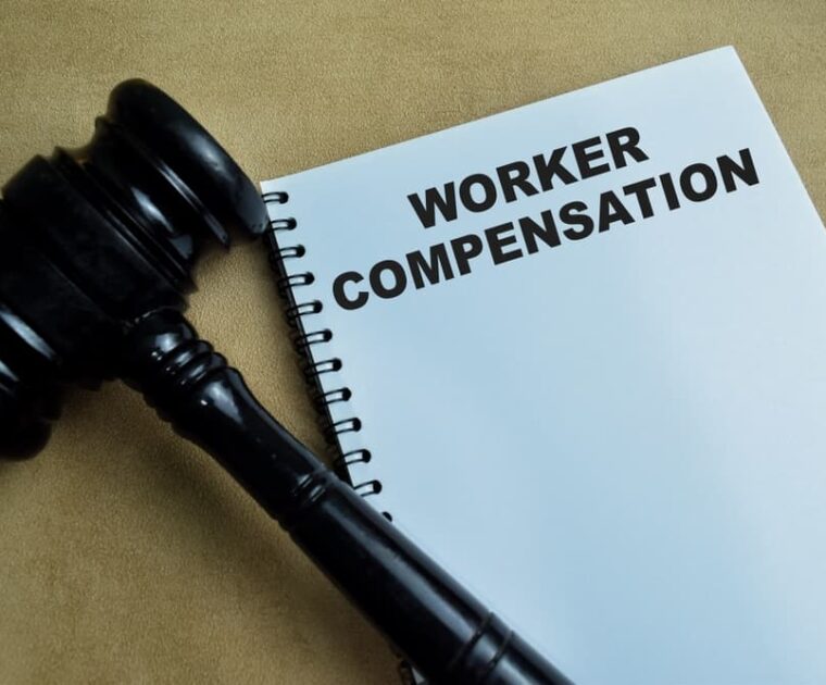 "Worker Compensation" concept written in a book on a wooden table.
