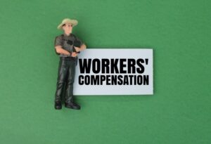 Miniature people and white paper with the words workers' compensation