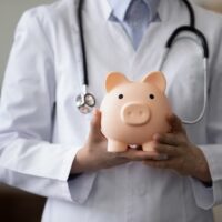 female doctor physician nurse wearing white uniform with stethoscope holding pink piggy bank, medical insurance concept, healthcare and medicine, hospital budget, clinic fees